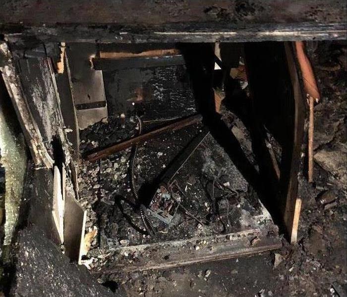Image depicts a badly burned cash register, black and charred.  