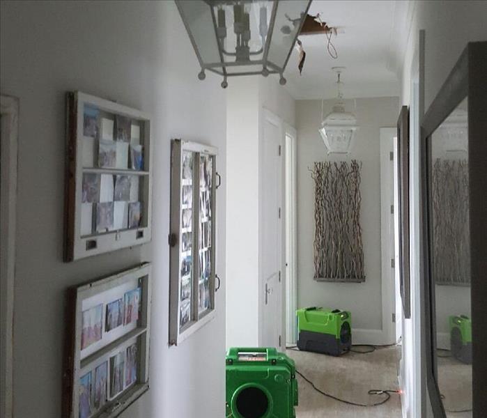 Photo shows a carpeted hallway with soot damage and 2 green SERVPRO air scrubbers in position.